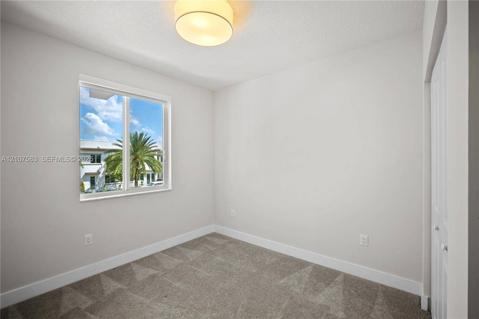 10270 NW 66th Street, #110, Doral, Doral, FL 33178 Neutral-toned interior space featuring neutral wall-to-wall carpeting, a single-pane sliding window, a circular flush-mount ceiling light fixture, and a built-in closet with double-panel doors