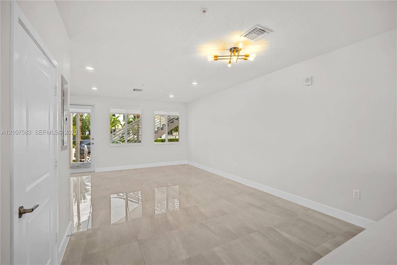 10270 NW 66th Street, #110, Doral, Doral, FL 33178 Open-concept interior featuring large-format tile flooring, recessed lighting, a modern multi-bulb ceiling fixture, and dual windows with exterior access via a glass-panel door