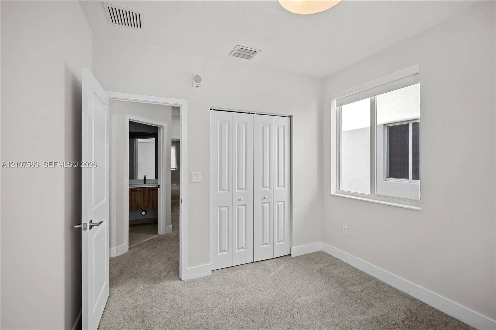 10270 NW 66th Street, #110, Doral, Doral, FL 33178 Neutral-toned carpeted flooring, bi-fold closet doors, and a double-pane window