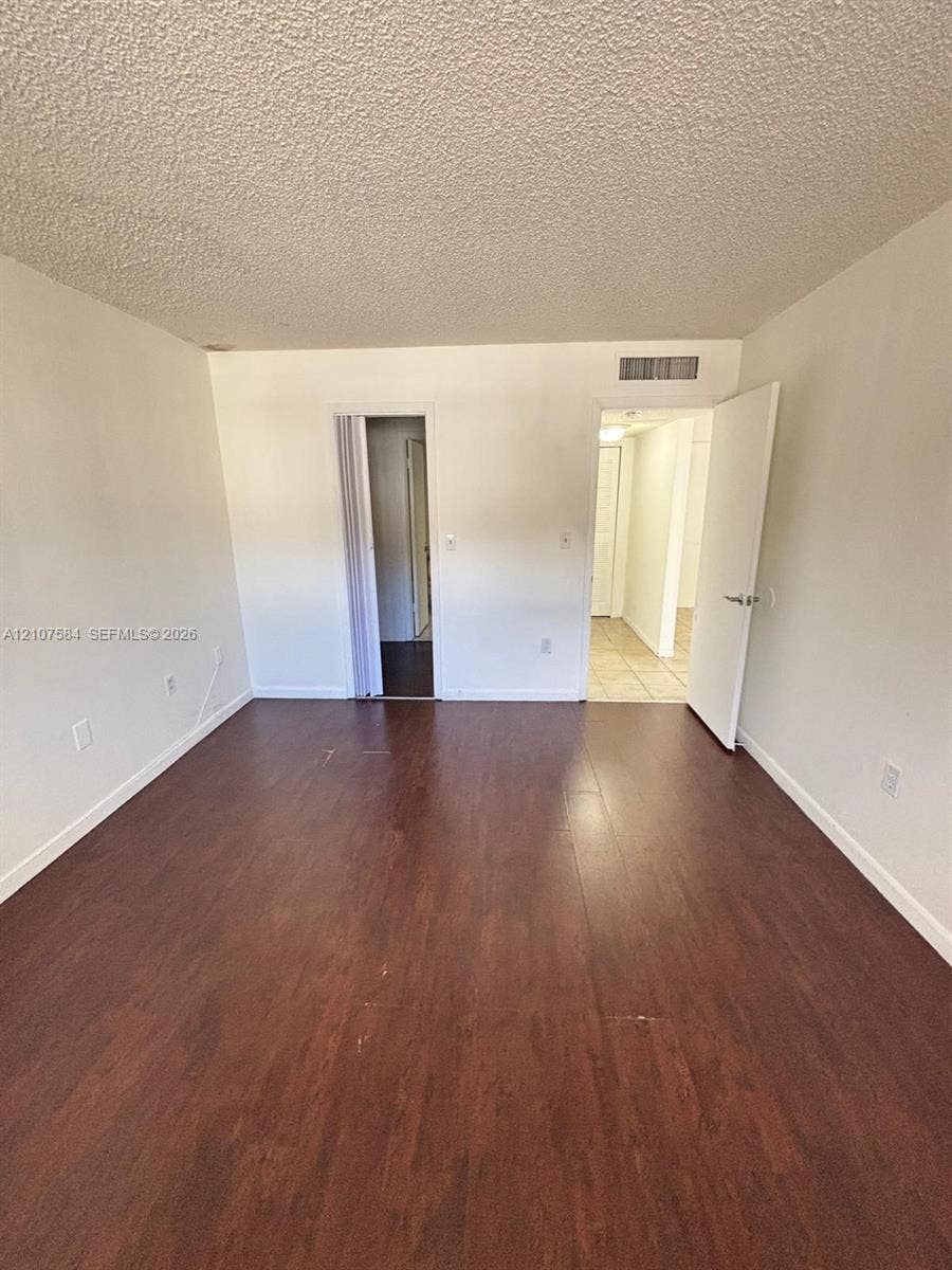 Interior space featuring wood-finish flooring, white walls, and a textured ceiling