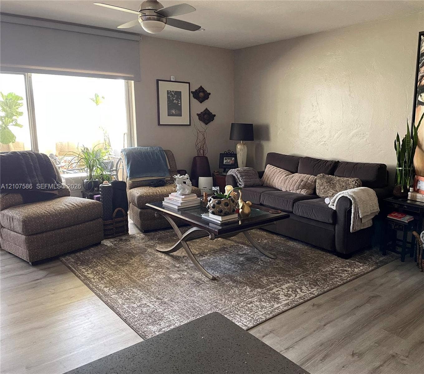 8335 SW 72nd Avenue, #306D, Miami, Miami, FL 33143 Living space featuring light-toned wood-finish flooring, a large window with a roller shade, and a ceiling fan