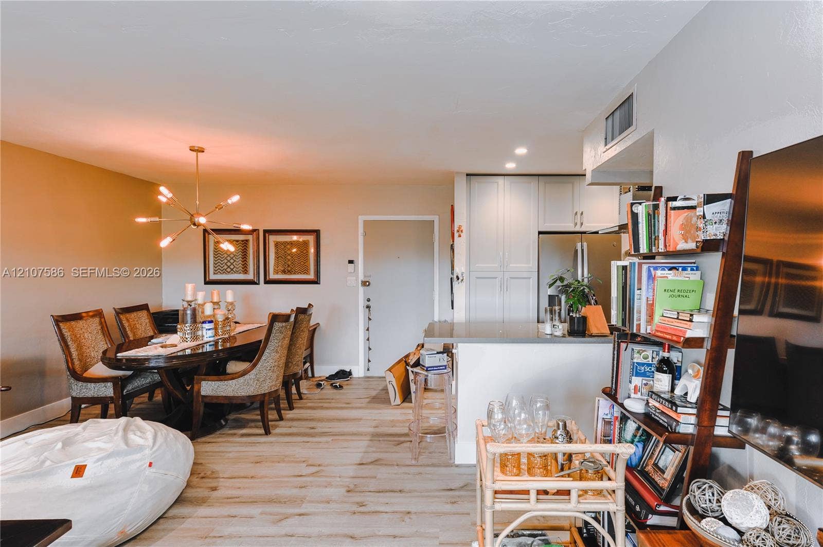 8335 SW 72nd Avenue, #306D, Miami, Miami, FL 33143 Open-concept area featuring wood-finish flooring, a multi-arm sputnik-style chandelier, and a breakfast bar with stone-finish countertops