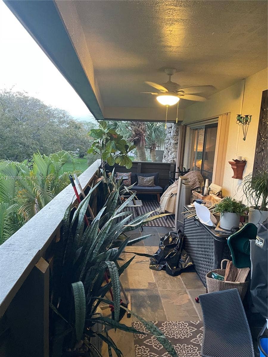 8335 SW 72nd Avenue, #306D, Miami, Miami, FL 33143 Covered balcony featuring stone-tile flooring, ceiling-mounted lighting with integrated fan, and solid wood-panel railing