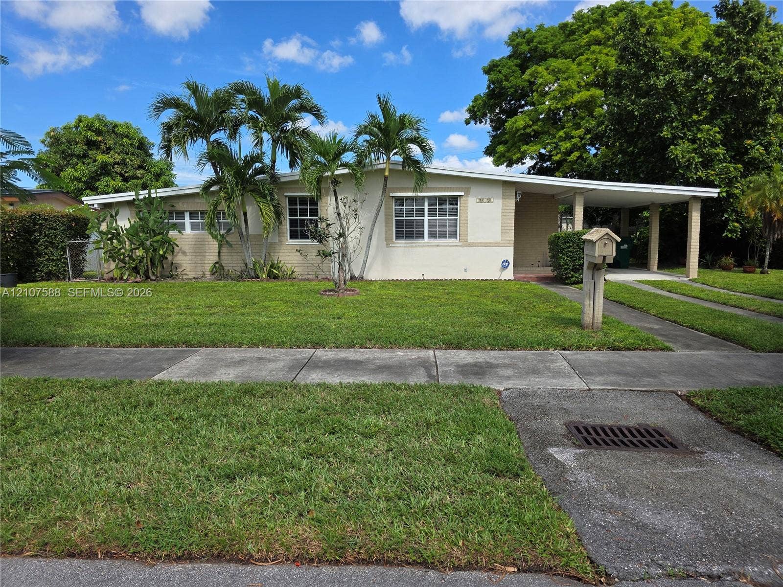 10721 SW 43rd Lane, Miami, FL 33165 Single-story exterior with a painted brick facade, low-slope roof, multi-pane windows, and an attached covered carport