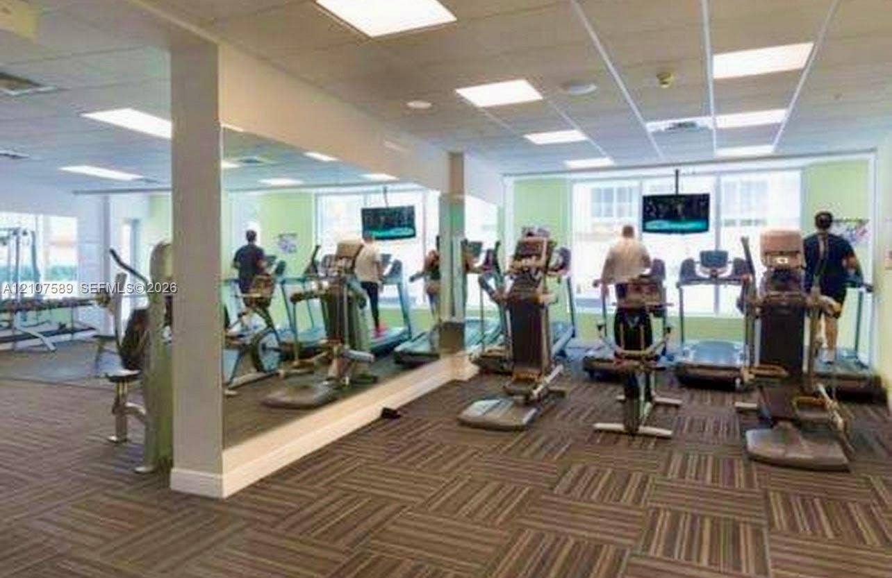 1750 N Bayshore Drive, #1218, Miami, Miami, FL 33132 Fitness center featuring wall-to-wall mirrors, patterned carpet tiles, drop ceiling with integrated lighting, and expansive windows