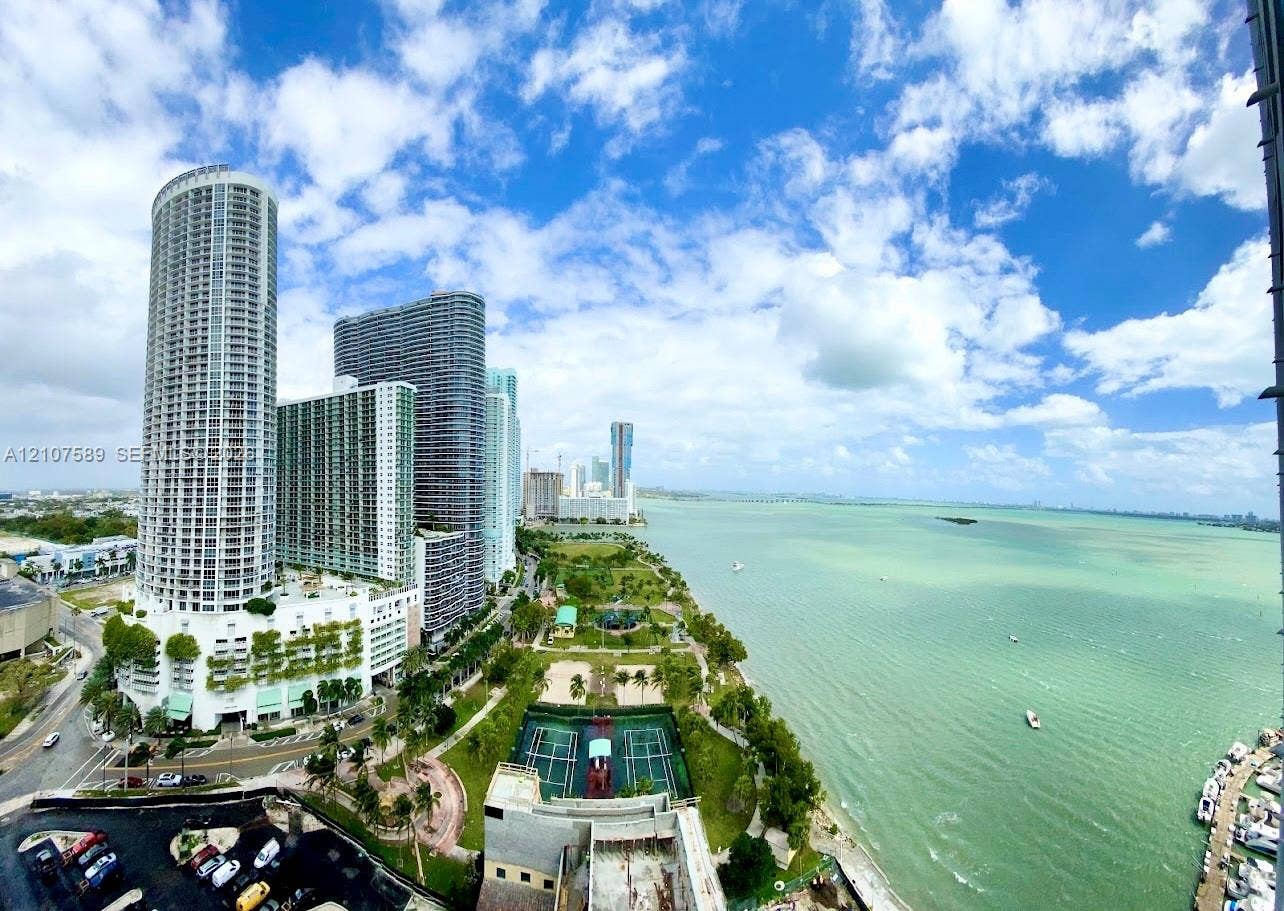 1750 N Bayshore Drive, #1218, Miami, Miami, FL 33132 Panoramic coastal scenery featuring open water, a shoreline park, tennis courts, and high-rise urban architecture