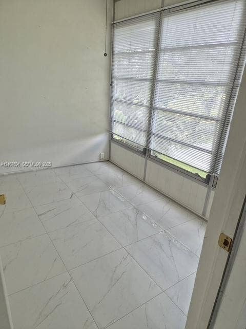 5003 NW 35th Street, #506, Lauderdale Lakes, FL 33319 Large-format white stone-finish tile flooring, expansive windows with integrated adjustable metal blinds, and smooth white walls