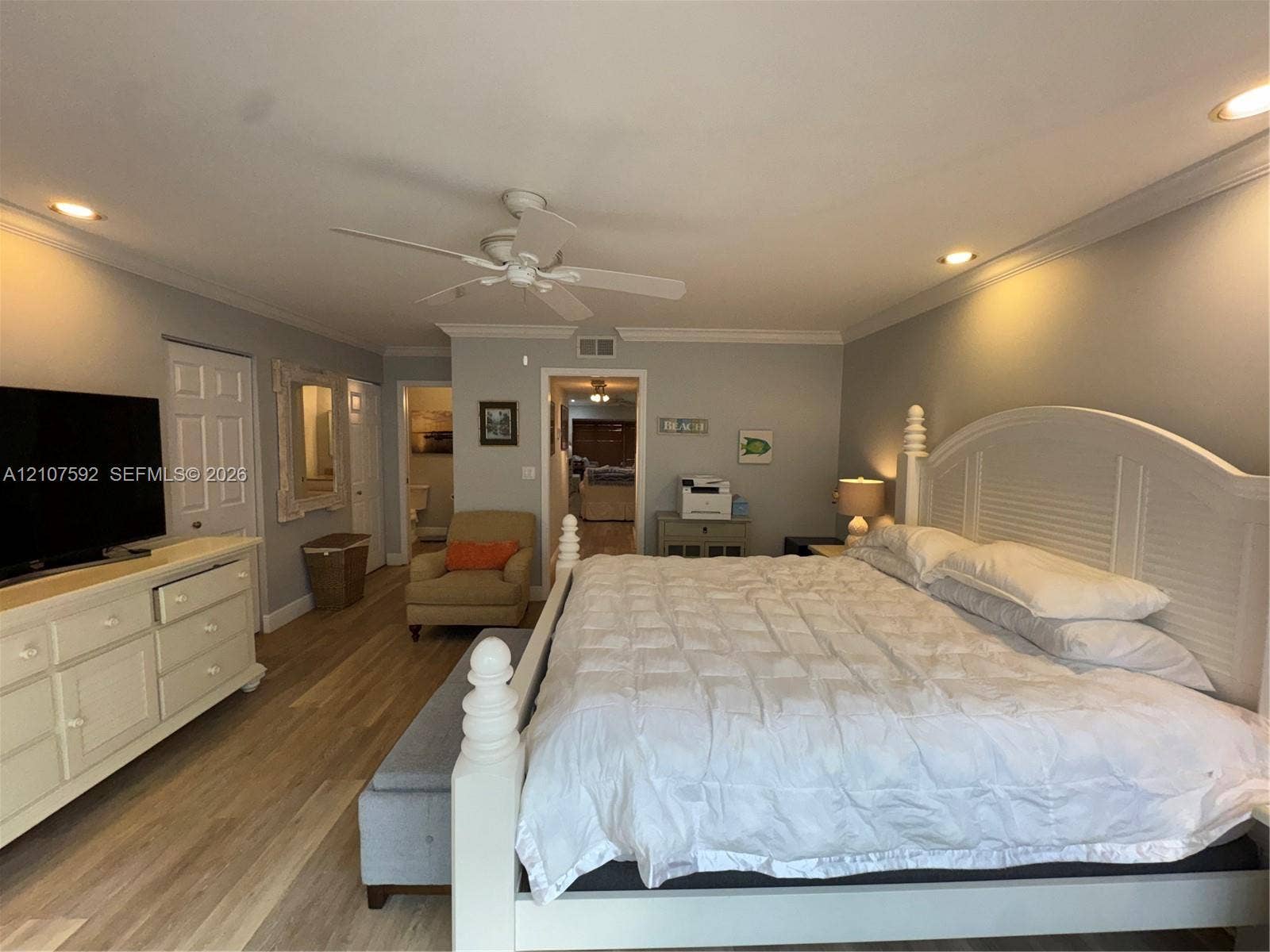 Wood-finish flooring, recessed ceiling lighting, crown molding, and a white ceiling fan