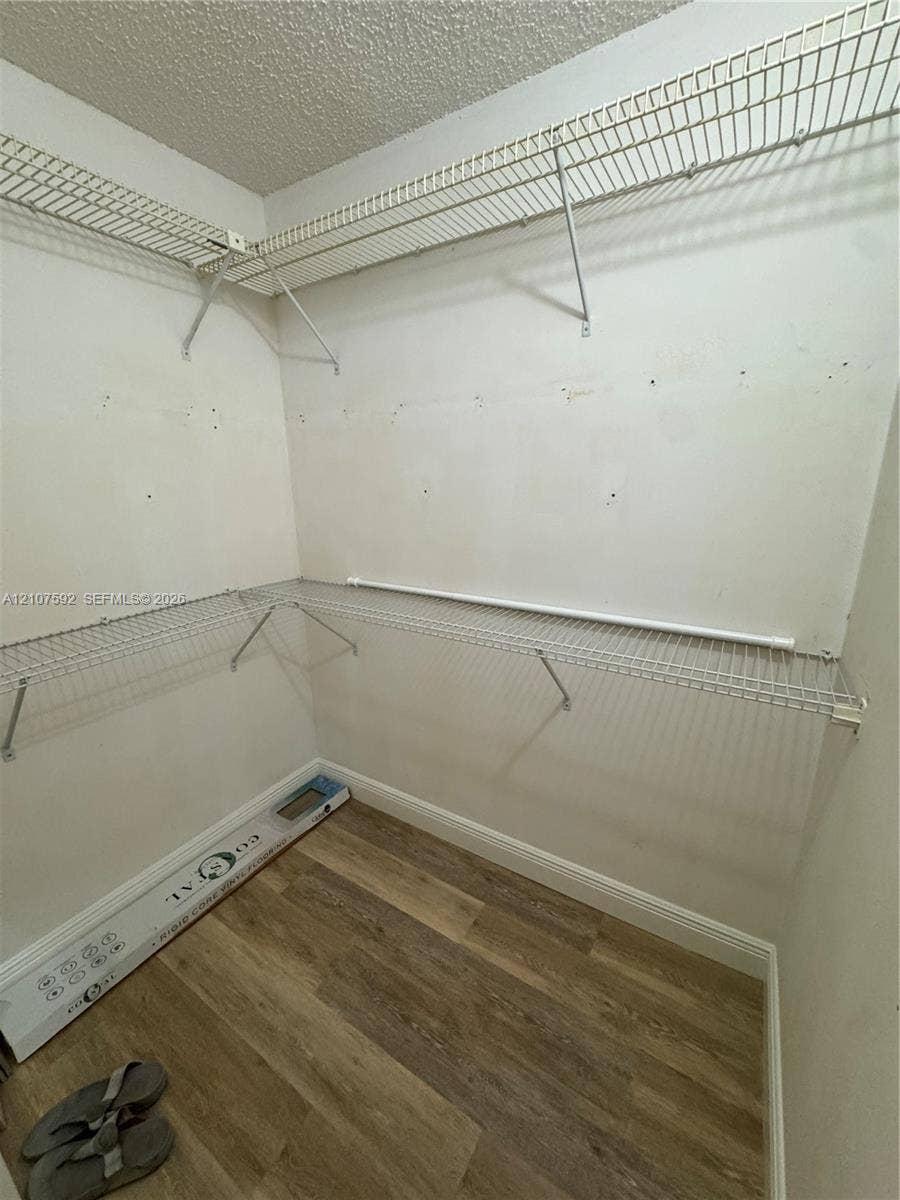 Walk-in closet featuring wood-finish flooring and two tiers of white wire shelving