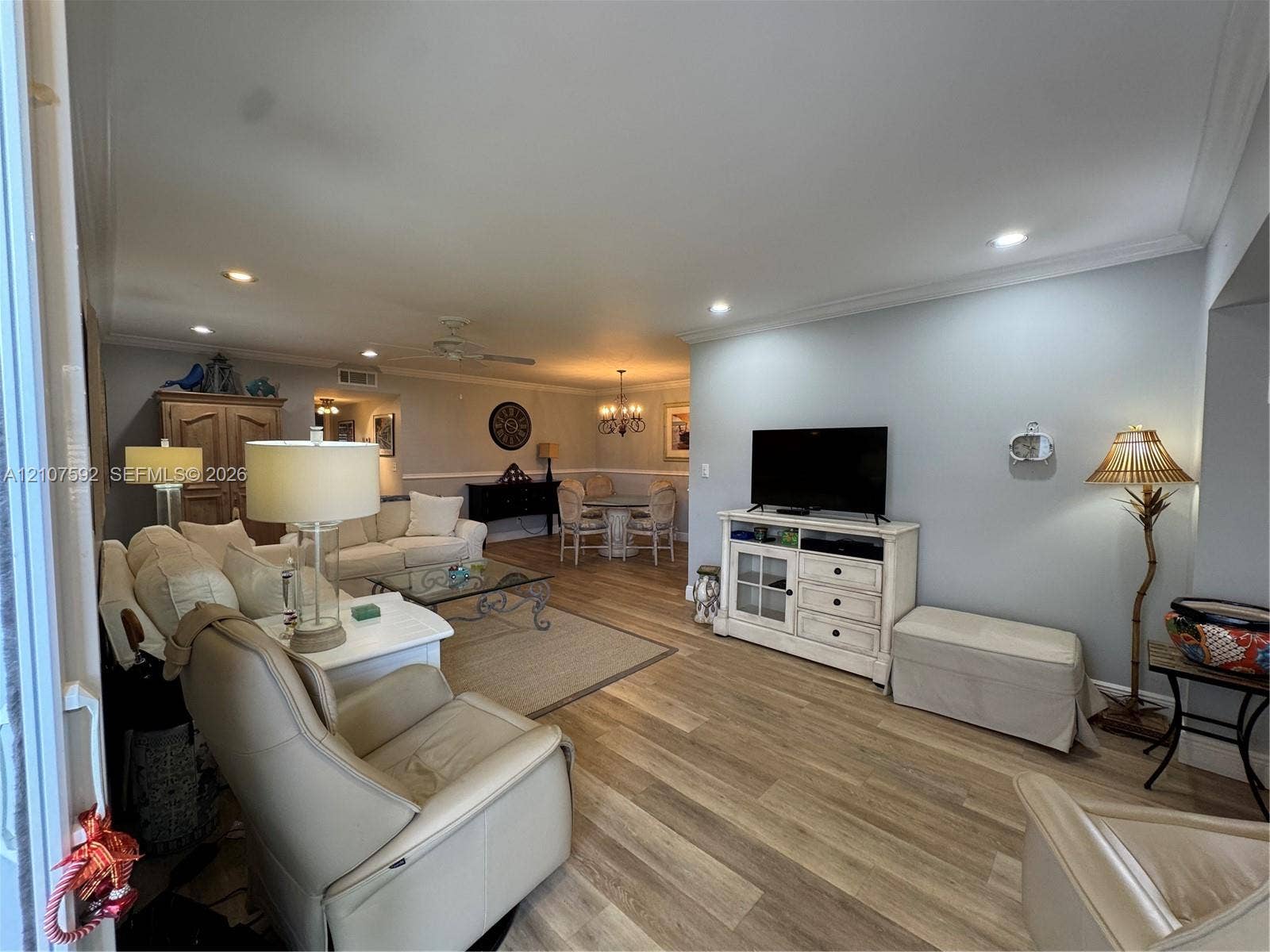 Open-concept living space featuring wood-finish flooring, recessed lighting, and crown molding