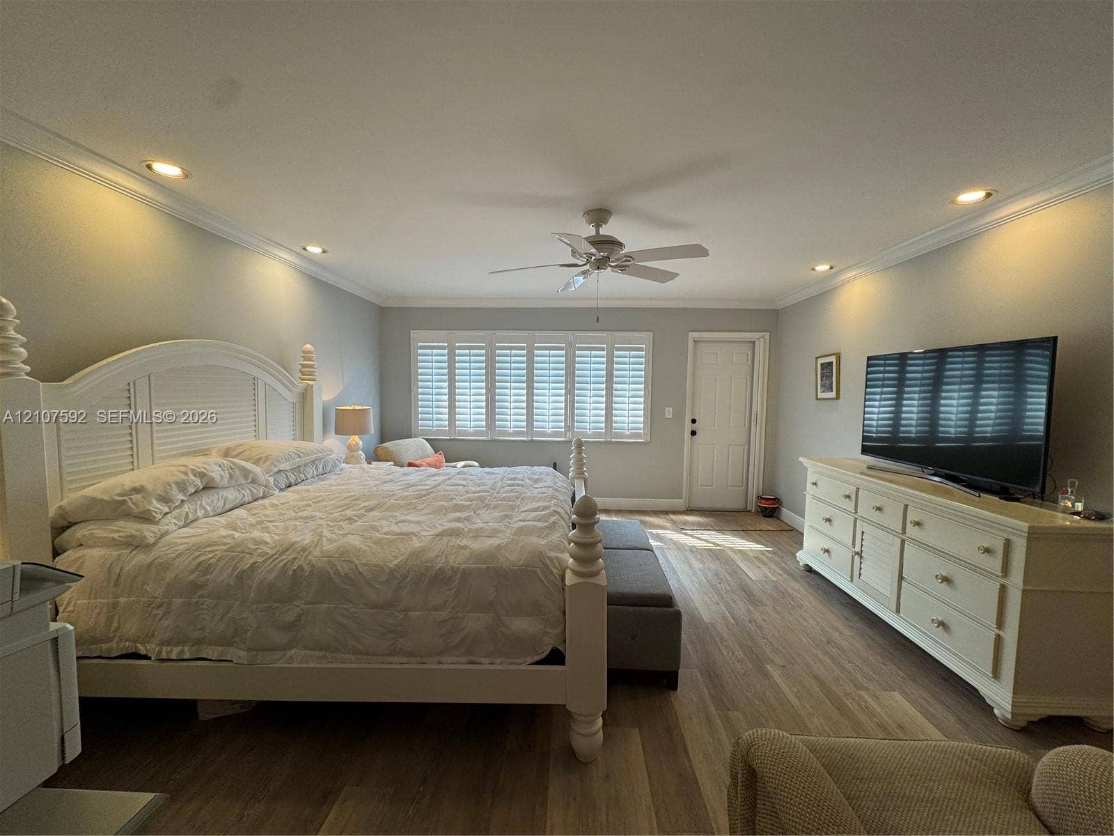 Room featuring wood-finish flooring, crown molding, recessed lighting, a ceiling fan, and plantation shutters