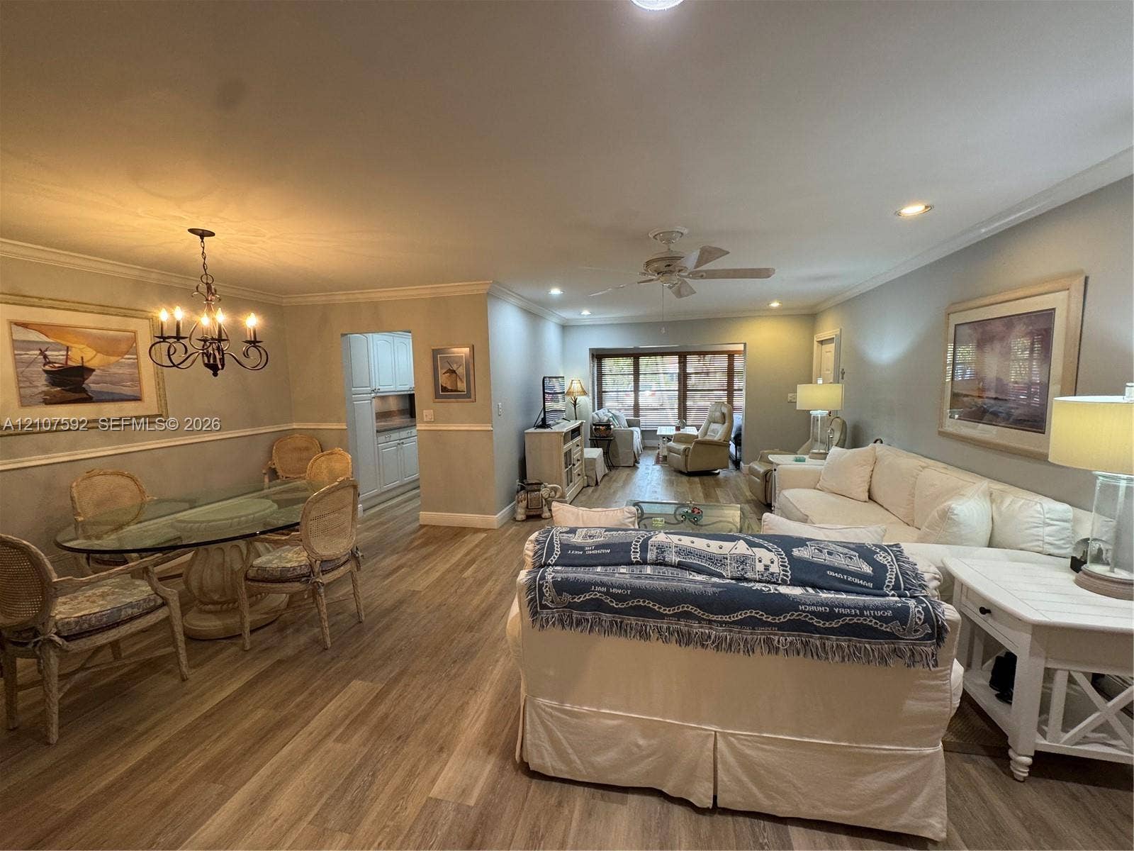 Open-concept interior featuring wood-finish flooring, crown molding, chair rail trim, recessed lighting, and a multi-arm chandelier