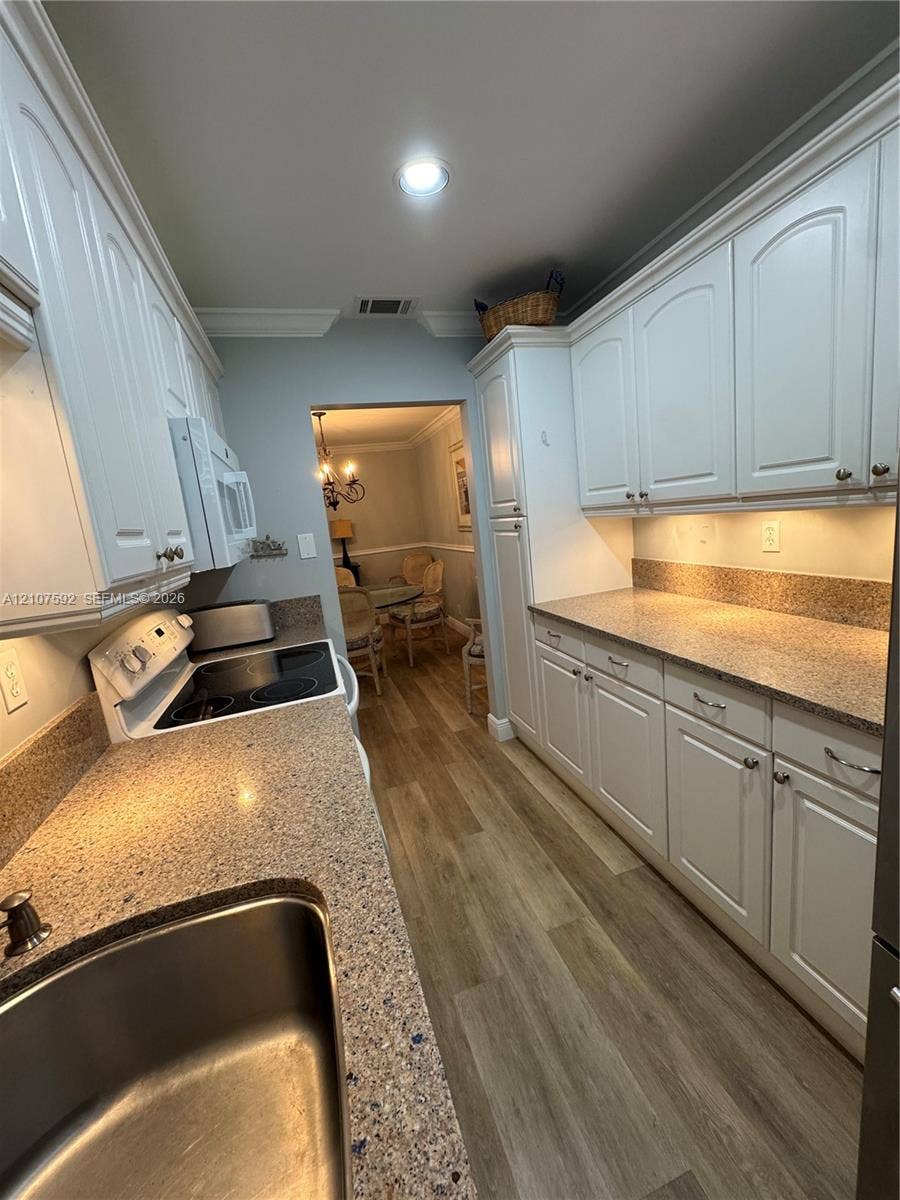 Kitchen featuring white cabinetry, stone-finish countertops, wood-finish flooring, recessed lighting, and a stainless steel sink