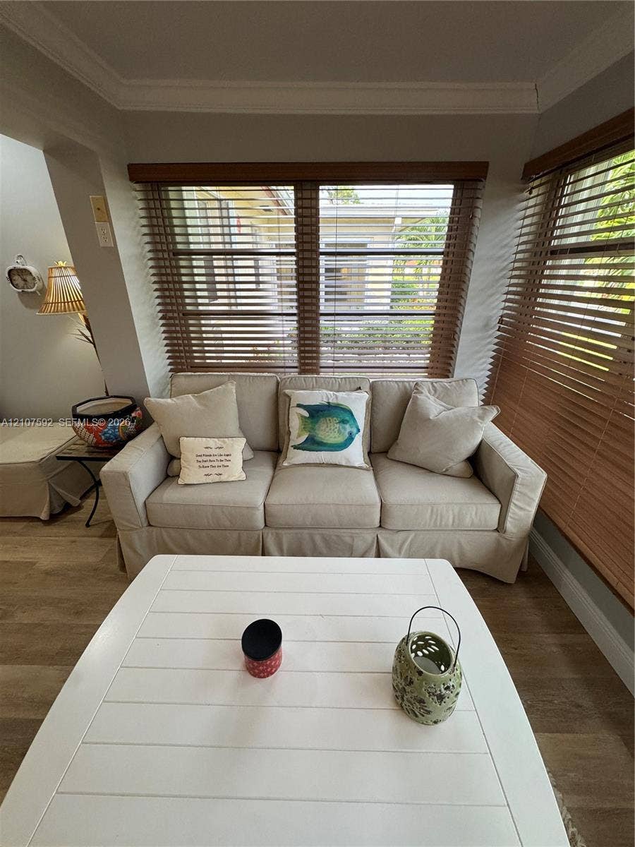 Wood-finish flooring, neutral wall tones, crown molding, and horizontal wood blinds