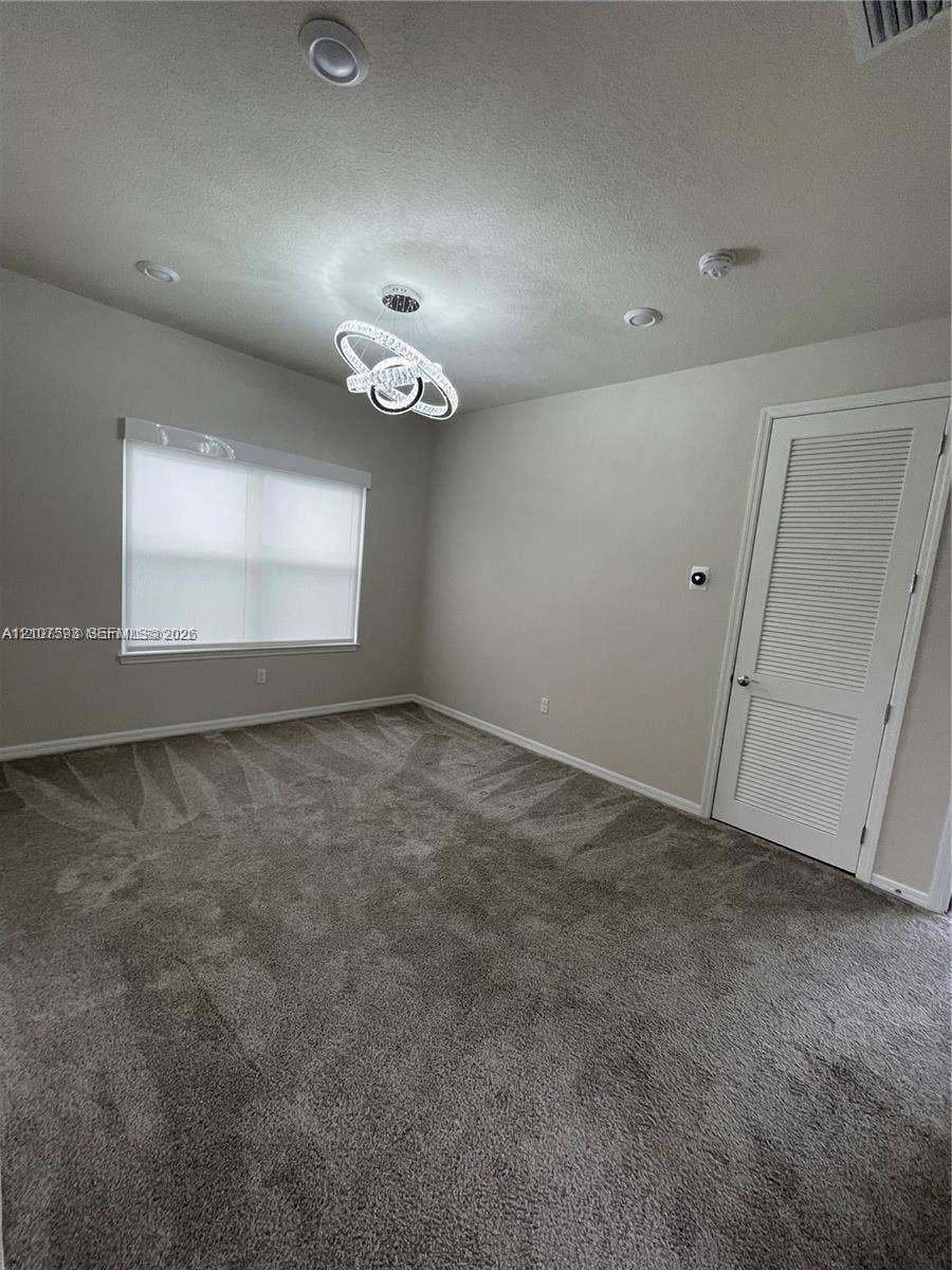 Interior space featuring wall-to-wall carpeting, a contemporary circular pendant light fixture, recessed ceiling lighting, and a louvered closet door