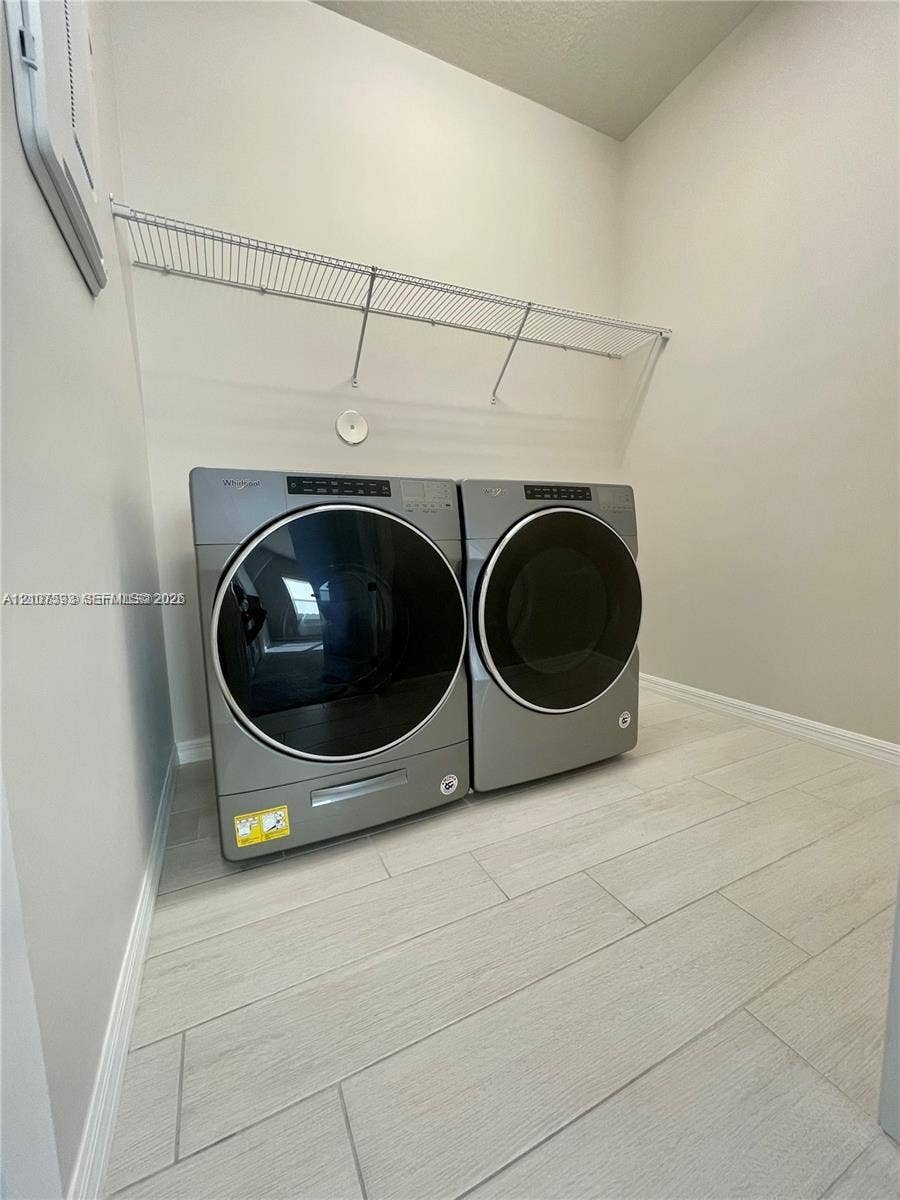 Laundry space featuring light-toned tile flooring and white wall-mounted wire shelving