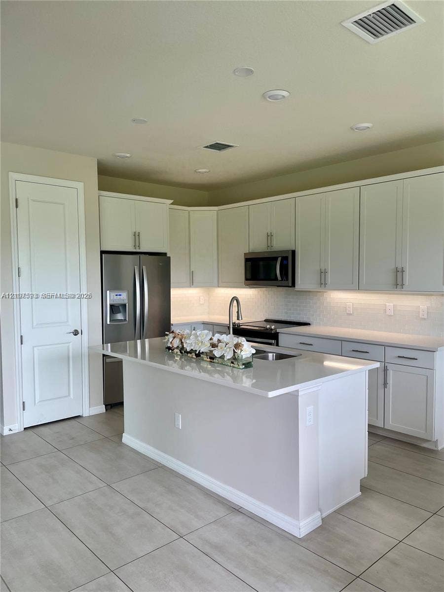 Kitchen featuring white cabinetry, quartz countertops, a central island with a stainless steel undermount sink, recessed lighting, and stainless steel appliances