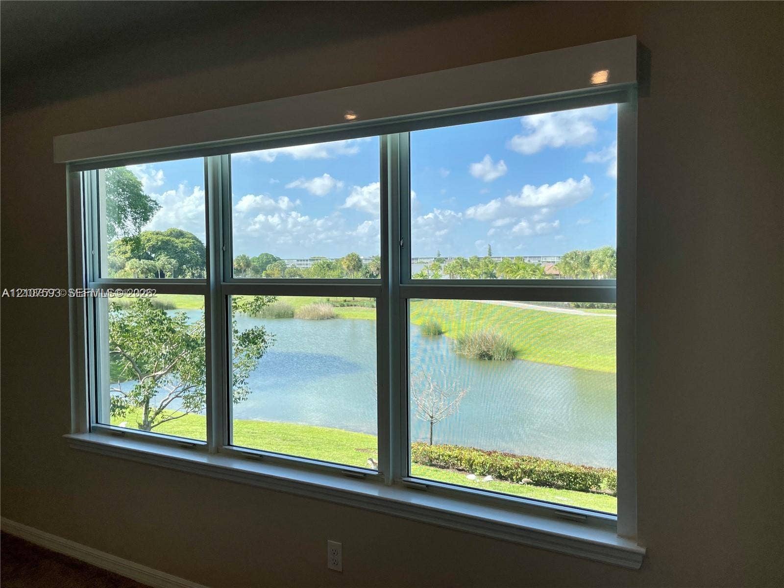 Large multi-pane window with white trim, featuring expansive water and landscape scenery