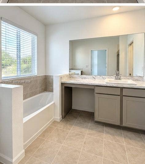1088 NW 208th Terrace, Miami Gardens, FL 33169 Bathroom featuring a soaking tub with tile surround, vanity with stone-patterned countertop, under-mount sink, large wall-mounted mirror, and tile flooring