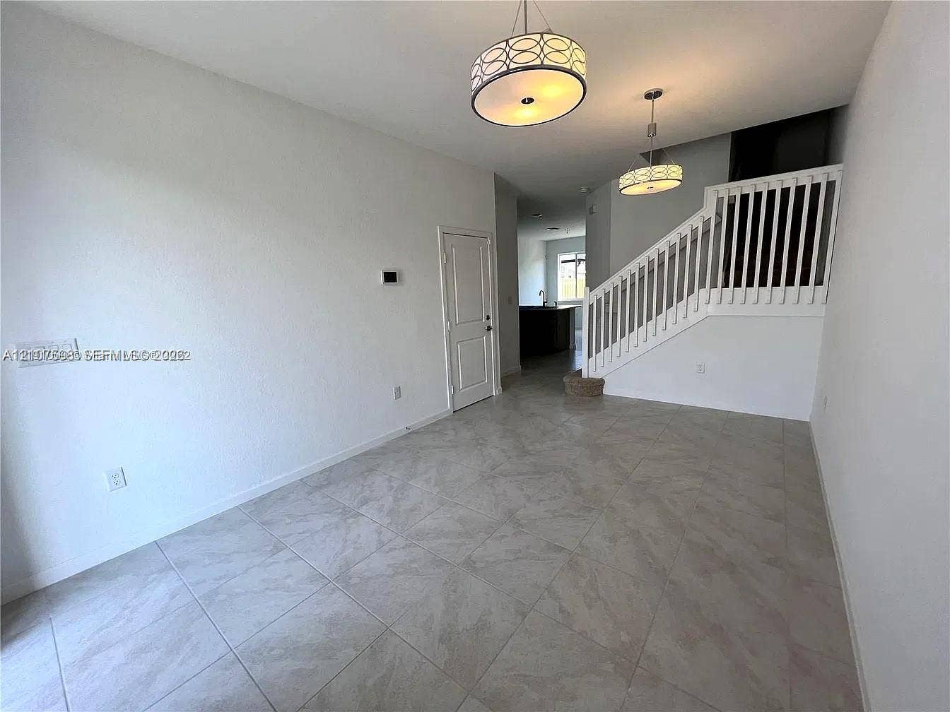 1088 NW 208th Terrace, Miami Gardens, FL 33169 Large-format tile flooring, dual drum pendant lighting, and a staircase featuring a white wooden balustrade