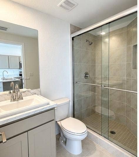 1088 NW 208th Terrace, Miami Gardens, FL 33169 Bathroom featuring a vanity with light-toned cabinetry, solid surface countertop with integrated basin, shower with sliding glass doors and ceramic wall tile, and built-in shower niche