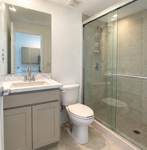 1088 NW 208th Terrace, Miami Gardens, FL 33169 Bathroom featuring a vanity with stone-patterned countertop, under-mount sink, chrome faucet, and a walk-in shower with a sliding glass door and tiled walls