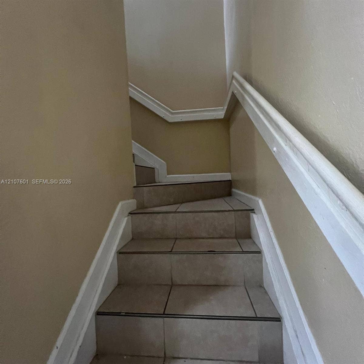 7080 NW 177th Street, #203-13, Hialeah, FL 33015 Staircase featuring large-format neutral tile treads, white painted millwork, and a sturdy white handrail