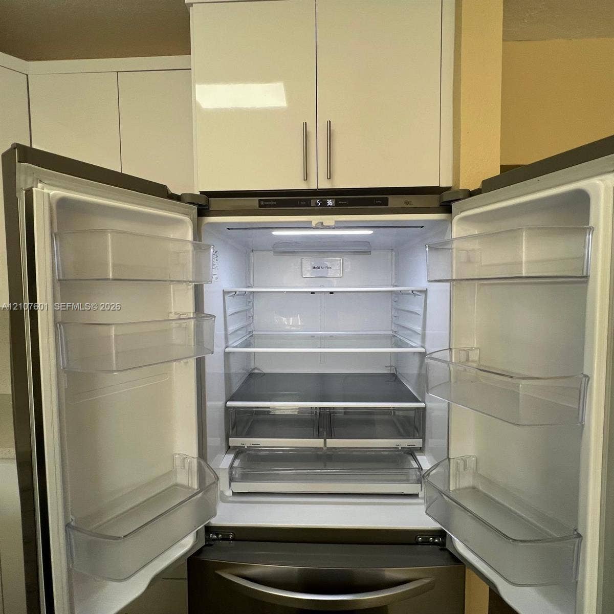 7080 NW 177th Street, #203-13, Hialeah, FL 33015 Stainless steel French-door refrigerator featuring adjustable glass shelving and high-gloss white cabinetry
