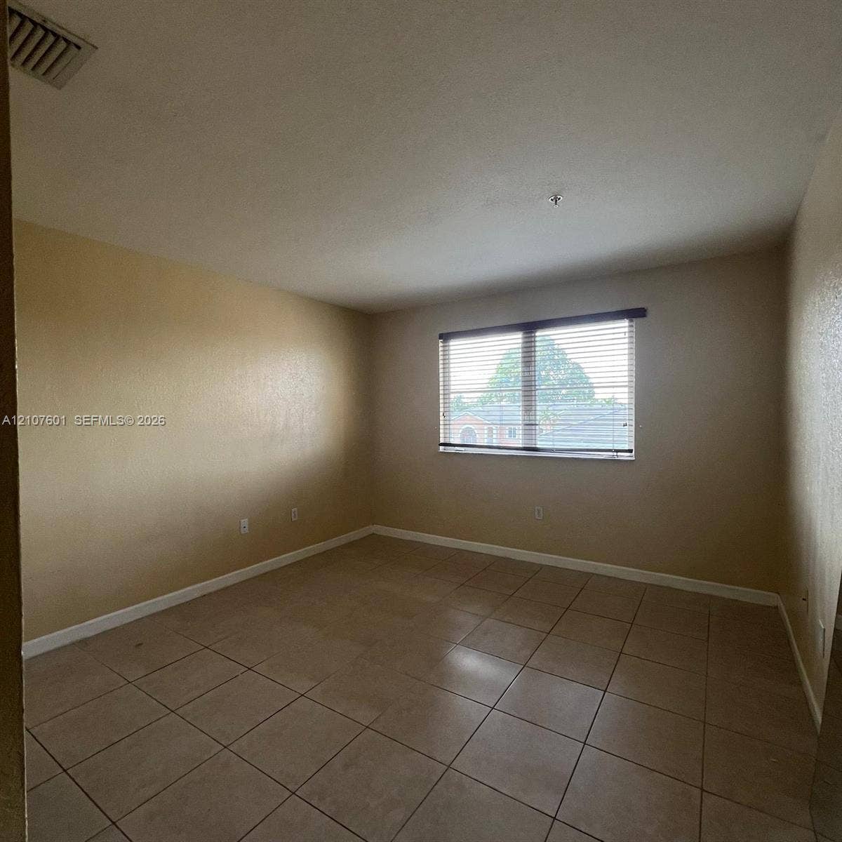 7080 NW 177th Street, #203-13, Hialeah, FL 33015 Neutral-toned room featuring light-colored tile flooring and a horizontal window with adjustable blinds