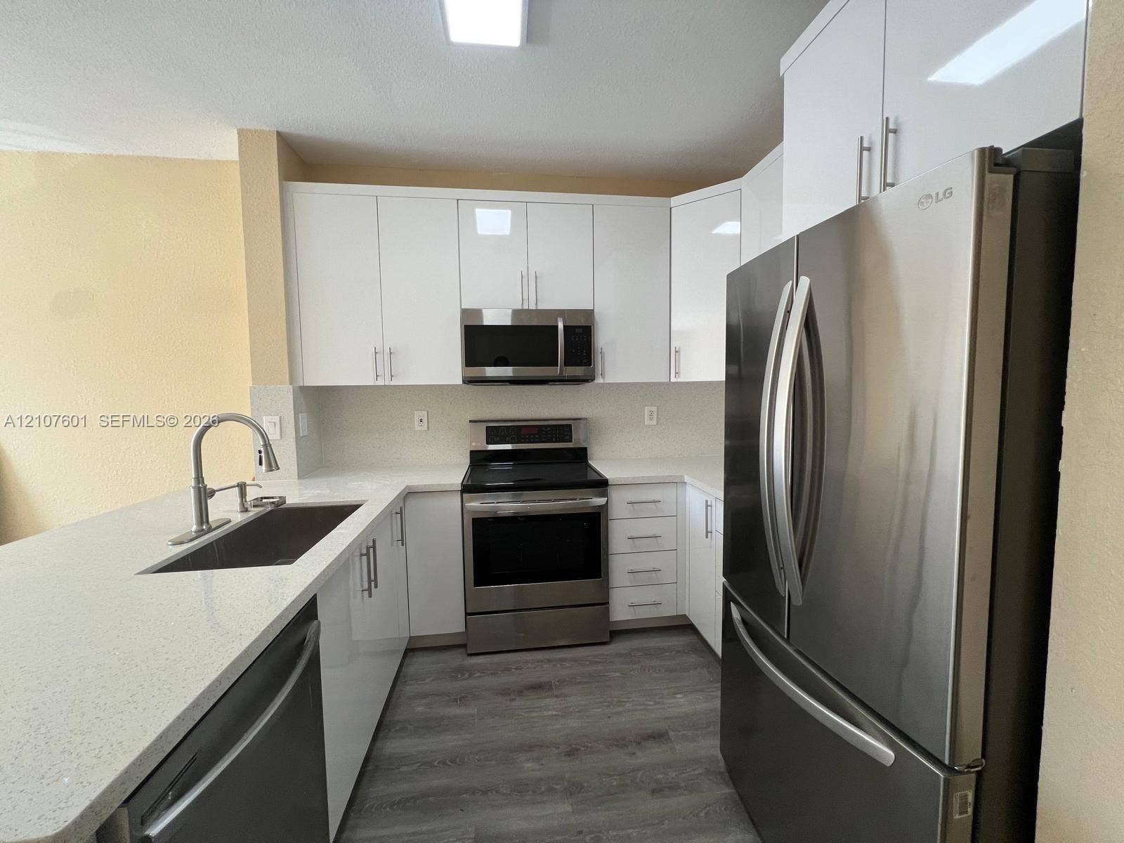 7080 NW 177th Street, #203-13, Hialeah, FL 33015 Kitchen featuring high-gloss white cabinetry, white stone countertops, stainless steel appliances, a stainless steel undermount sink with a gooseneck faucet, and grey wood-finish flooring