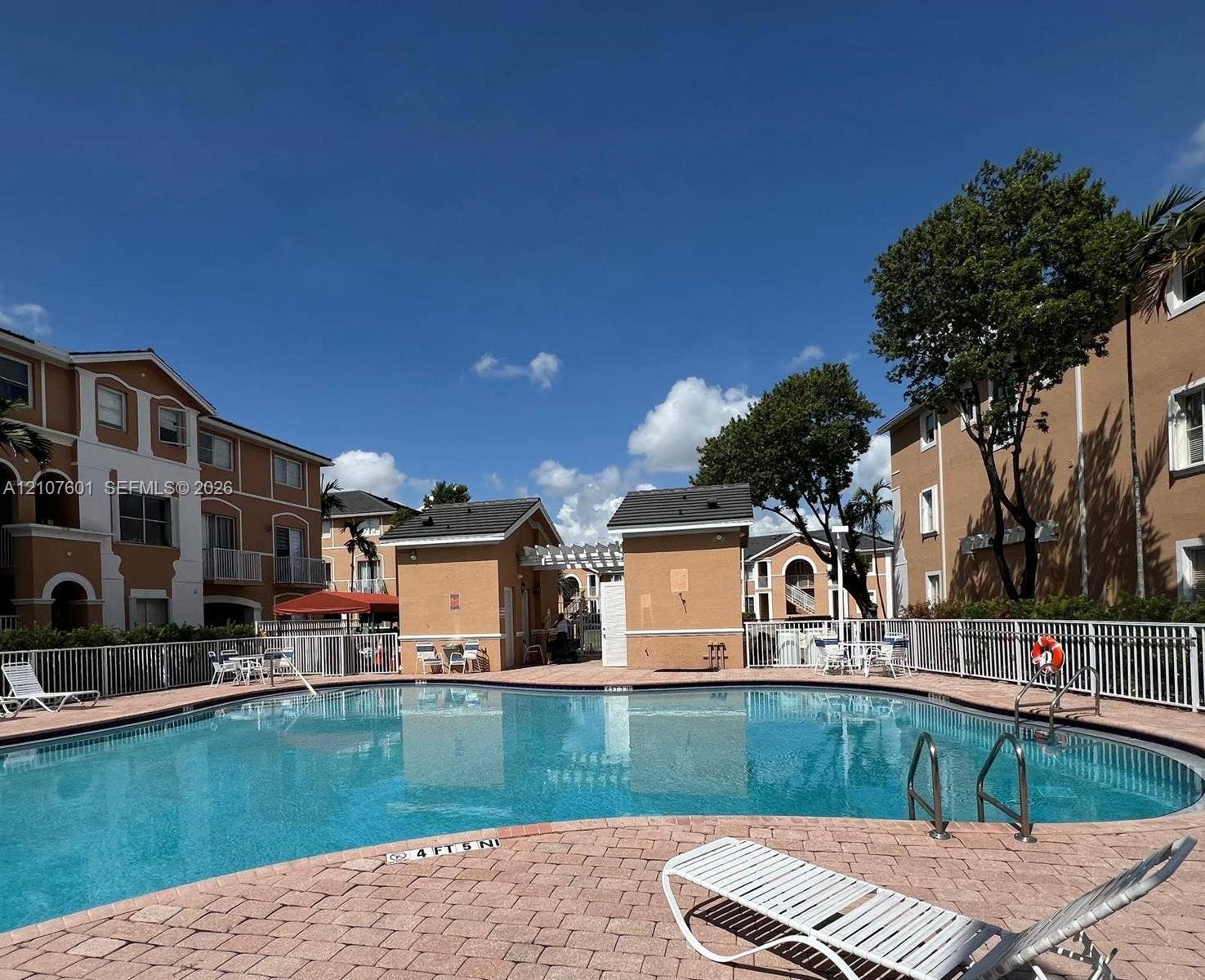 7080 NW 177th Street, #203-13, Hialeah, FL 33015 Swimming pool with paver decking, pergola-covered structure, and perimeter fencing
