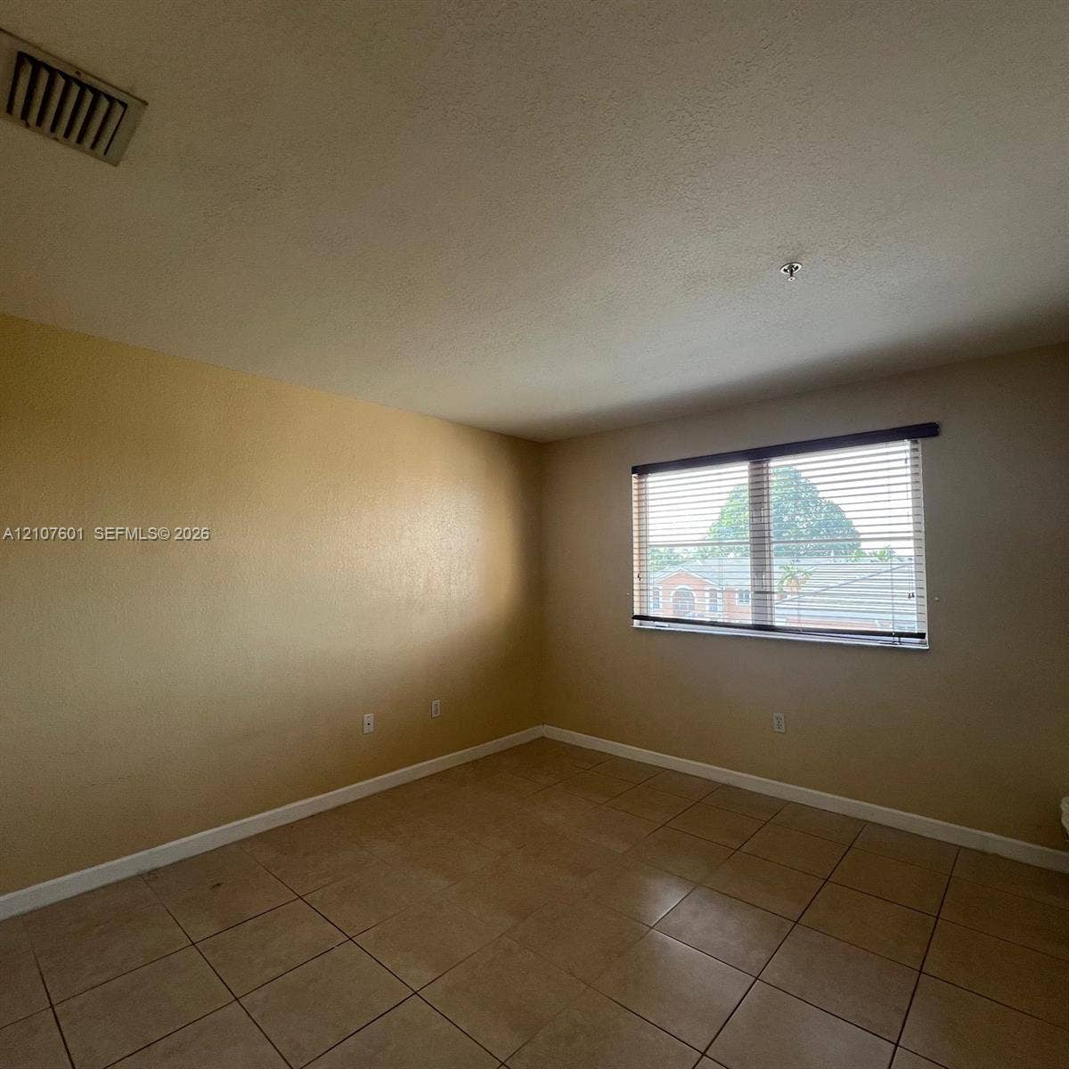 7080 NW 177th Street, #203-13, Hialeah, FL 33015 Neutral-toned interior space featuring light-colored ceramic tile flooring and a horizontal window with integrated blinds