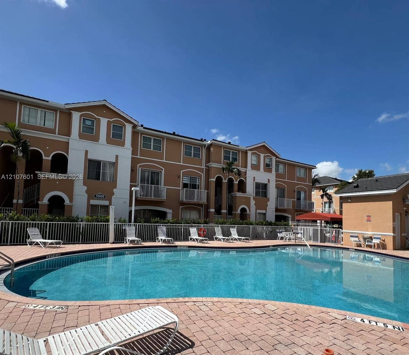 7080 NW 177th Street, #203-13, Hialeah, FL 33015 Community pool featuring a curved design, brick-paver decking, and metal fencing