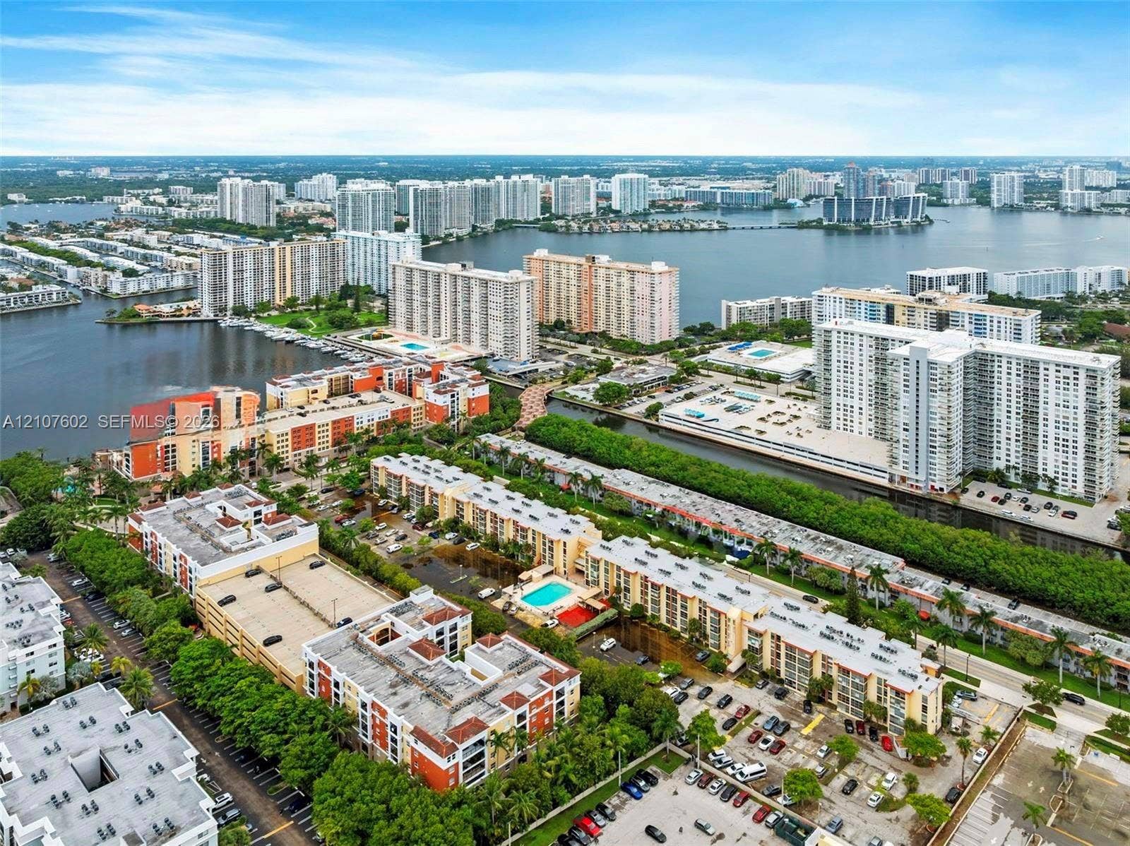 210 172nd Street, #542, Sunny Isles Beach, FL 33160 Aerial perspective of waterfront urban landscape featuring canals, residential mid-rise structures, landscaped grounds, and parking facilities