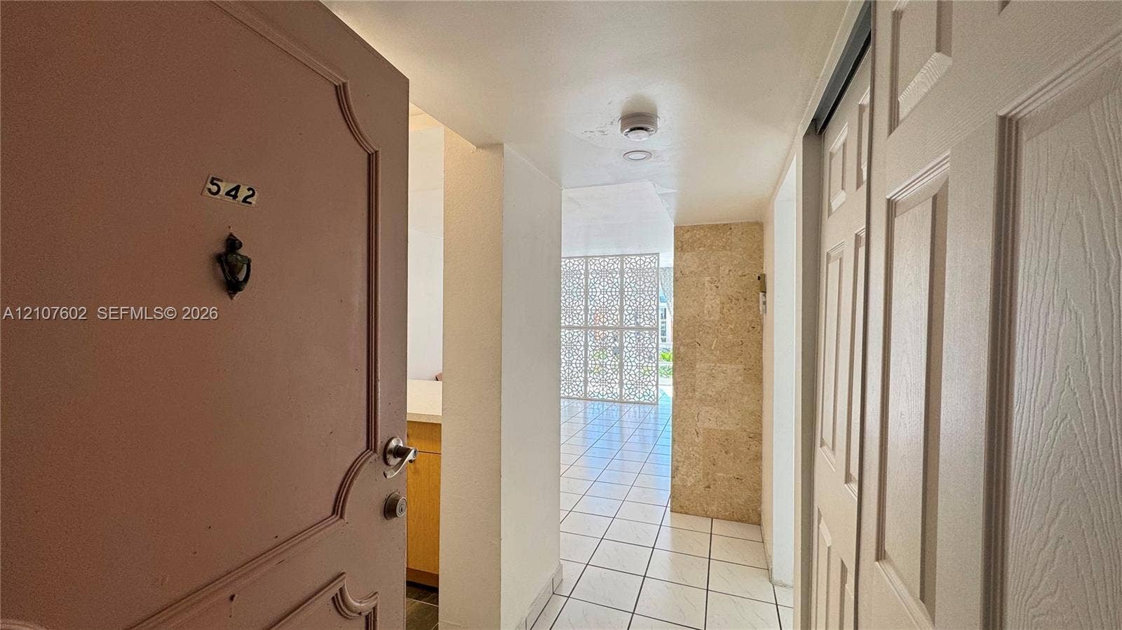 210 172nd Street, #542, Sunny Isles Beach, FL 33160 Entryway featuring a decorative metal screen, stone-tiled accent wall, recessed lighting, and tile flooring