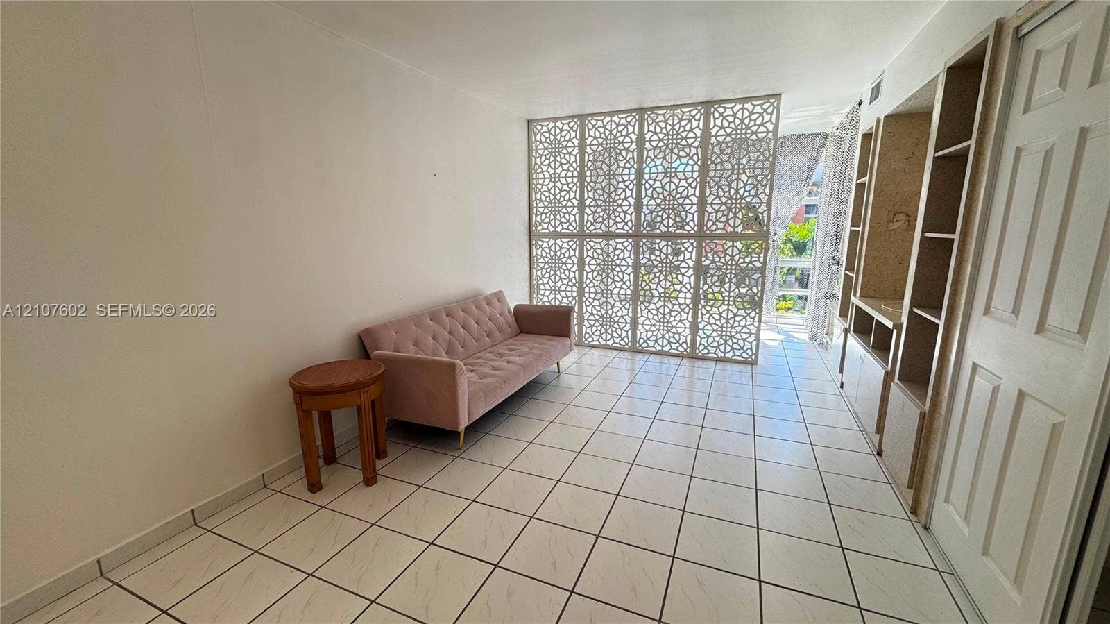 210 172nd Street, #542, Sunny Isles Beach, FL 33160 Interior space featuring large-format tile flooring, intricate laser-cut privacy screen, and built-in floor-to-ceiling shelving