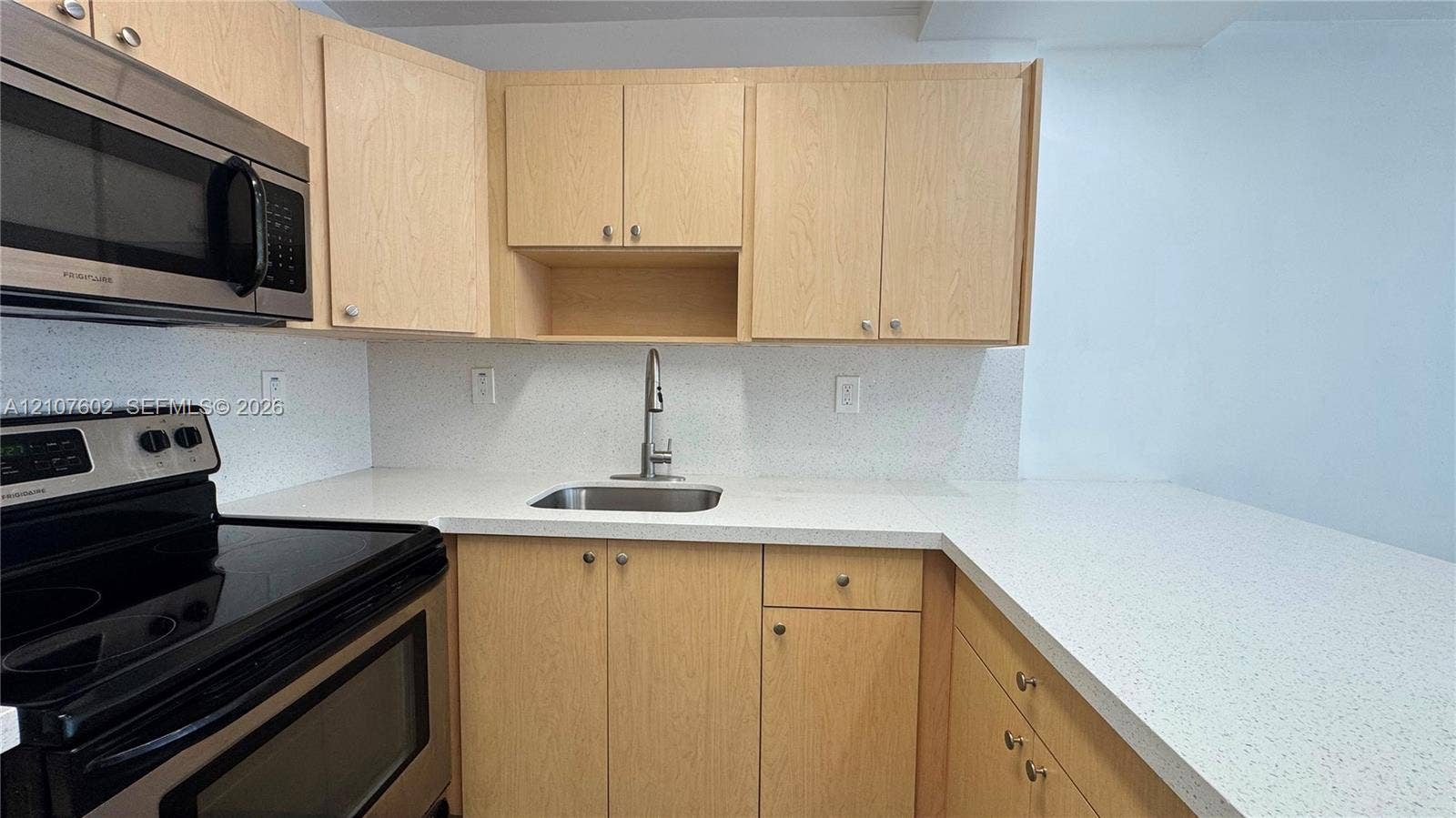 210 172nd Street, #542, Sunny Isles Beach, FL 33160 Kitchen featuring light-finish cabinetry, speckled solid-surface countertops, stainless steel appliances, and a single-basin undermount sink with a gooseneck faucet