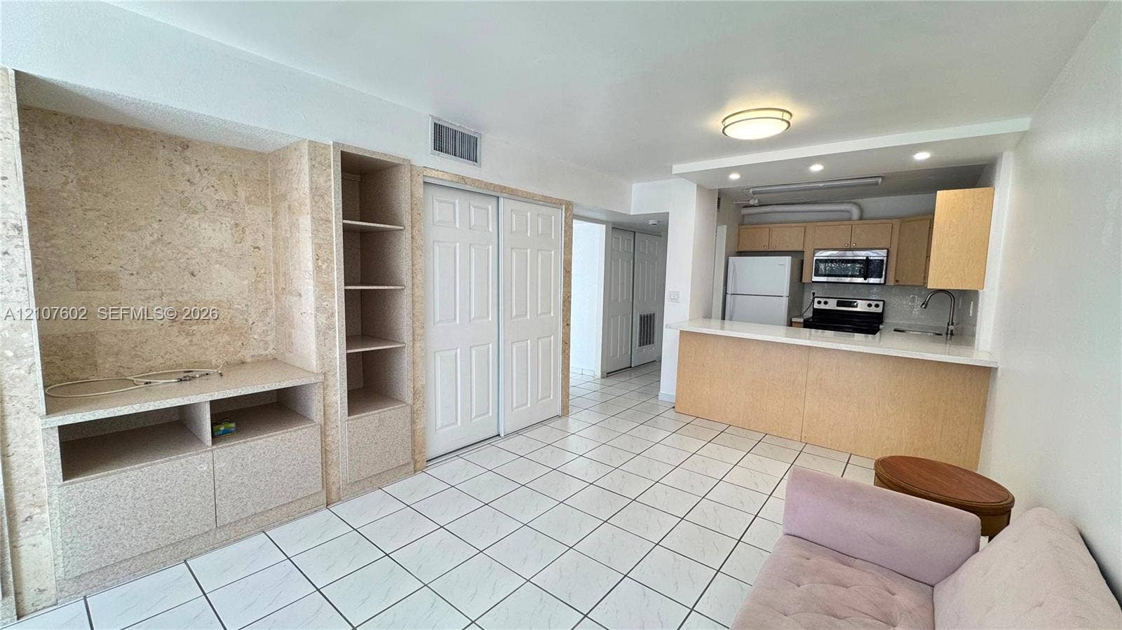 210 172nd Street, #542, Sunny Isles Beach, FL 33160 Open-concept kitchen featuring a breakfast bar, stone-tile-finished built-in cabinetry, ceramic tile flooring, and integrated stainless steel appliances