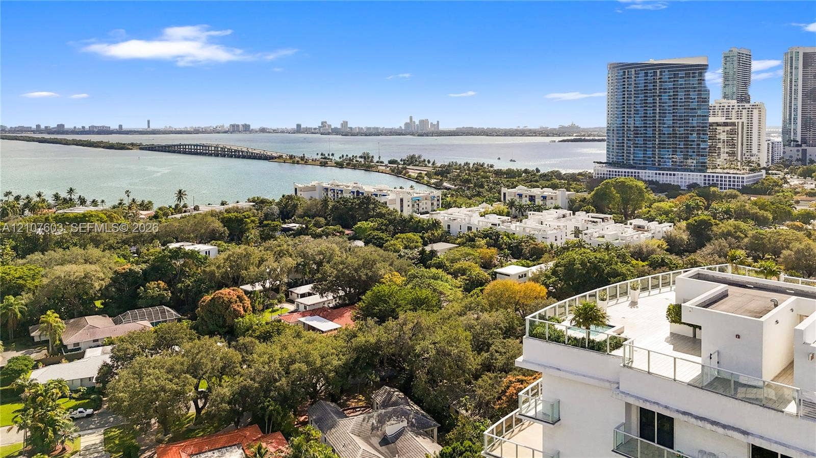 4250 Biscayne Boulevard, #1418, Miami, FL 33137 Aerial perspective featuring a multi-story residential building with a glass-railed rooftop terrace, integrated hardscaping, and surrounding mature tree canopy