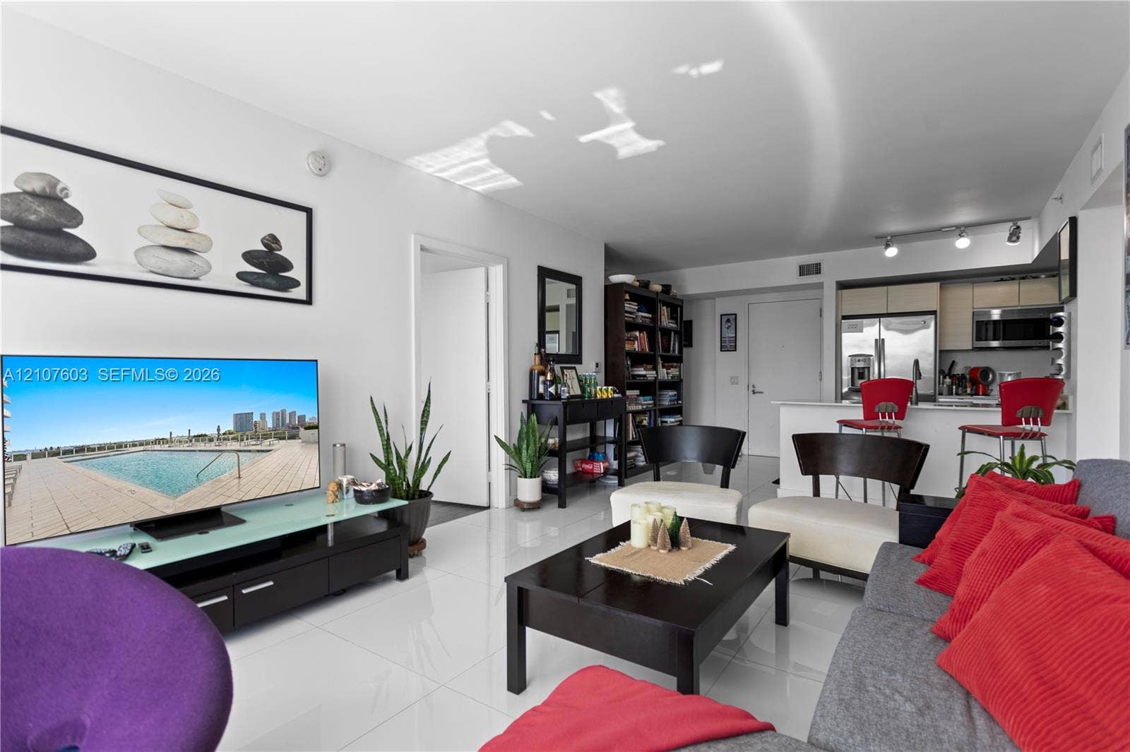 4250 Biscayne Boulevard, #1418, Miami, FL 33137 Open-concept living space featuring high-gloss tile flooring, recessed track lighting, and a kitchen peninsula with a white stone-finish countertop
