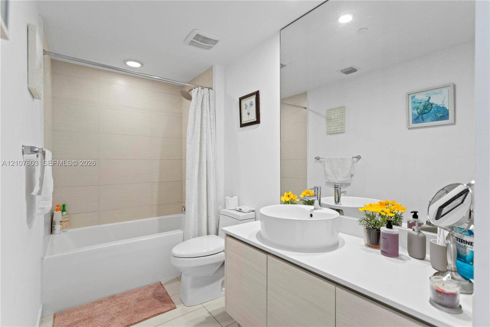 4250 Biscayne Boulevard, #1418, Miami, FL 33137 Bathroom featuring a vessel sink, quartz-finish countertop, light-toned cabinetry, floor-to-ceiling wall mirror, and a tub with a tile-surround wall