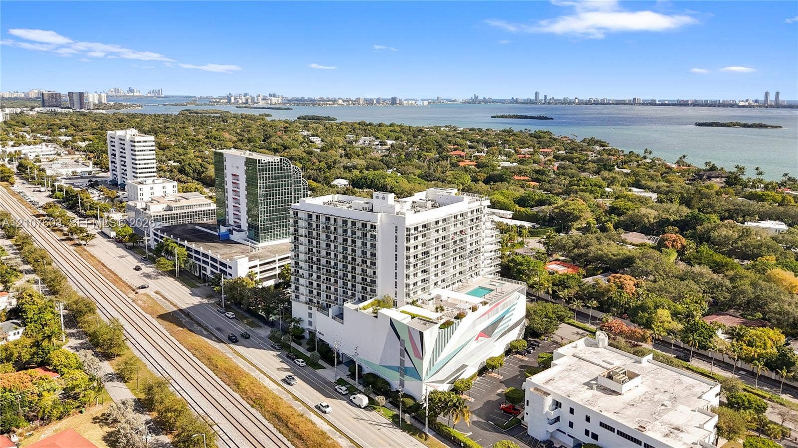 4250 Biscayne Boulevard, #1418, Miami, FL 33137 Aerial perspective featuring a mid-rise residential structure with a rooftop swimming pool and a prominent exterior geometric mural, located in a coastal setting