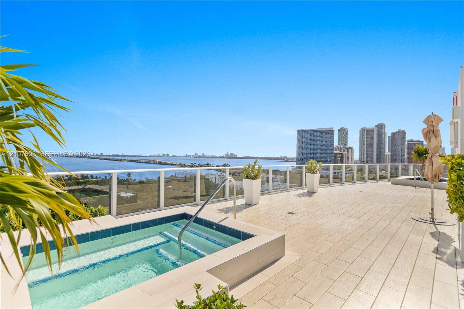 4250 Biscayne Boulevard, #1418, Miami, FL 33137 Expansive outdoor terrace featuring light-toned tile flooring, an in-ground spa with tile surround, and a glass-paneled railing