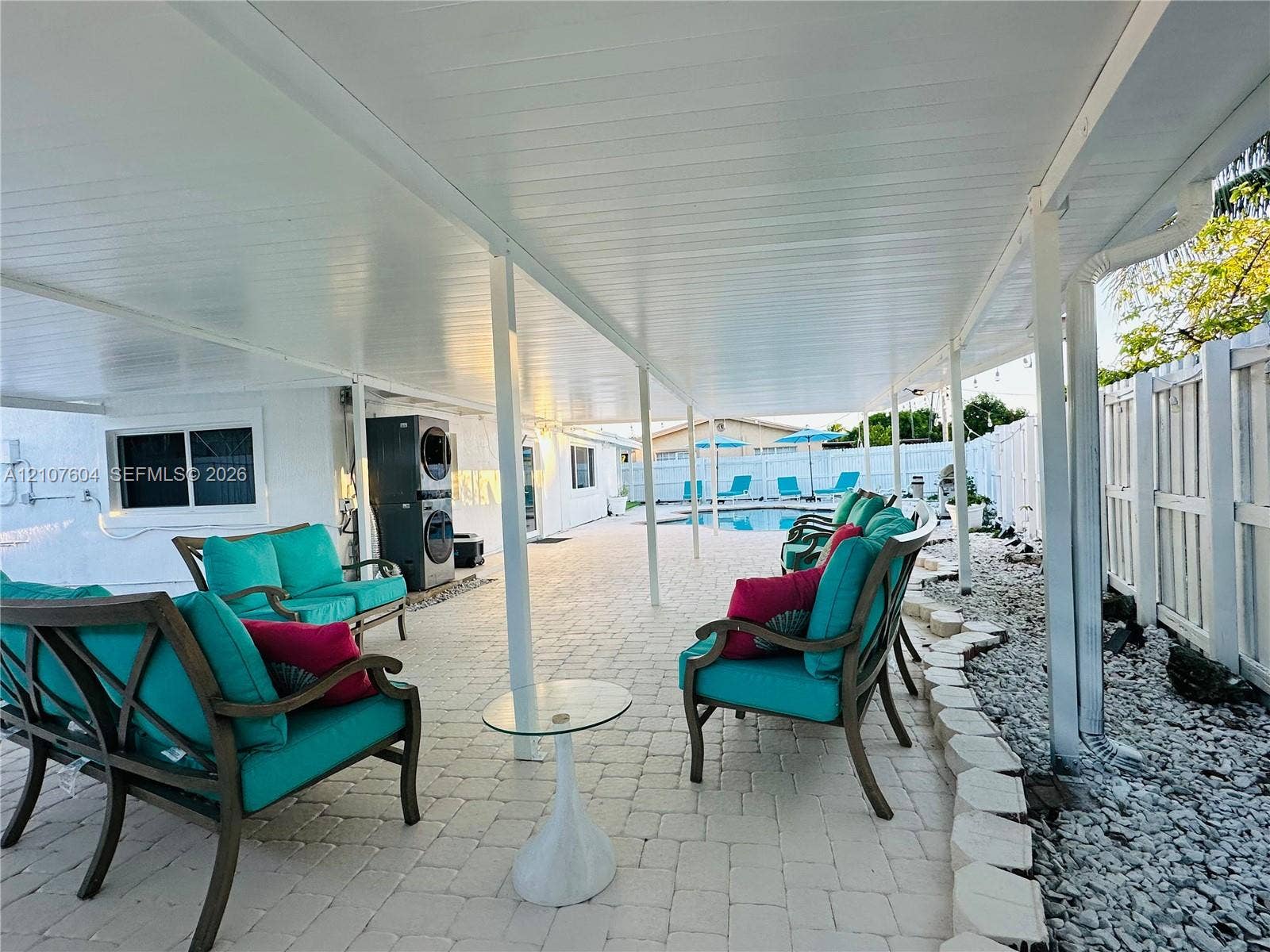 120 S 56th Avenue, Hollywood, Hollywood, FL 33023 Covered patio featuring paver flooring, a solid roof structure with support columns, white vinyl fencing, and an integrated swimming pool