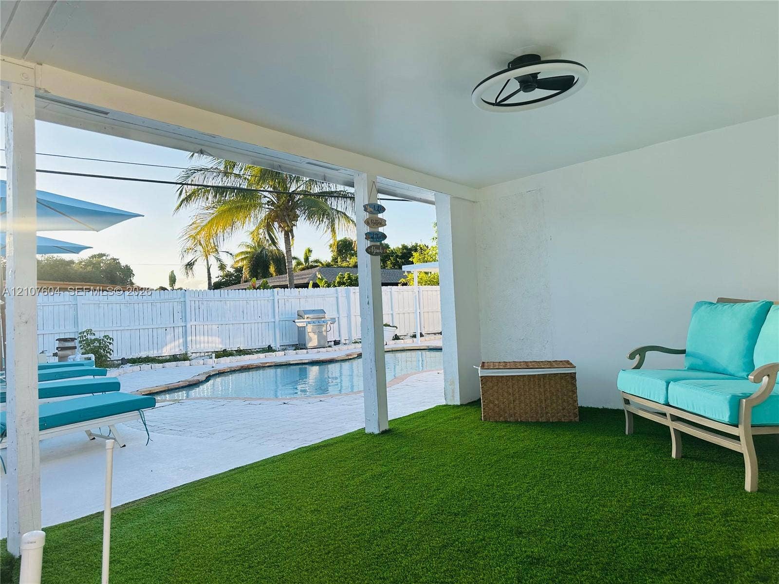 120 S 56th Avenue, Hollywood, Hollywood, FL 33023 Covered patio featuring artificial turf flooring, ceiling-mounted light fixture, white structural pillars, pool area, and white perimeter fencing