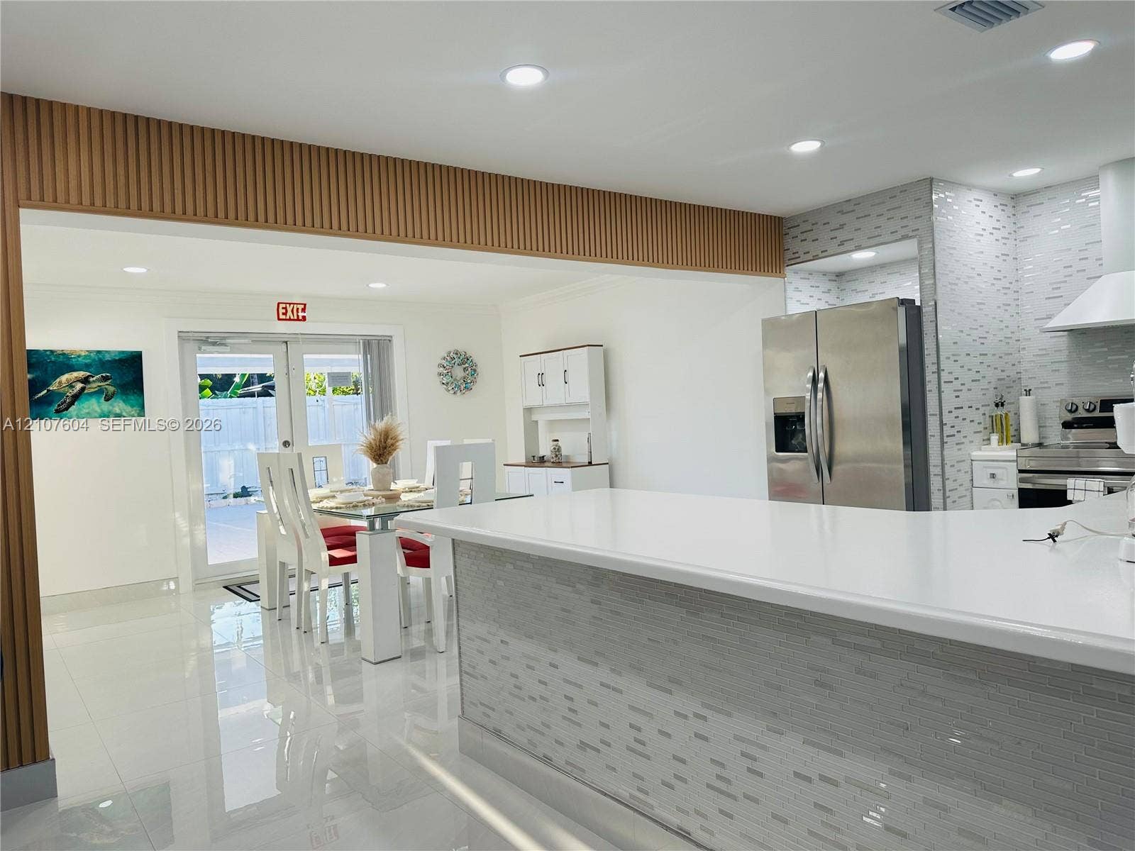 120 S 56th Avenue, Hollywood, Hollywood, FL 33023 Kitchen featuring a quartz countertop island, mosaic tile backsplash, stainless steel appliances, slat-style wood accent paneling, and polished tile flooring