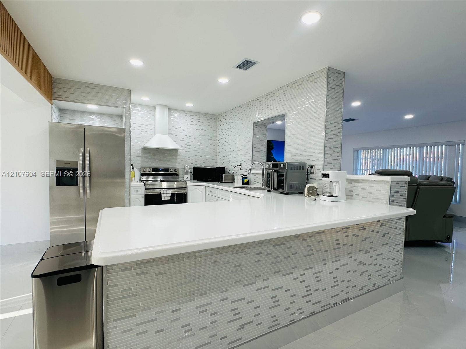 120 S 56th Avenue, Hollywood, Hollywood, FL 33023 Kitchen featuring a solid surface countertop, stainless steel refrigerator, white range hood, and mosaic tile backsplash