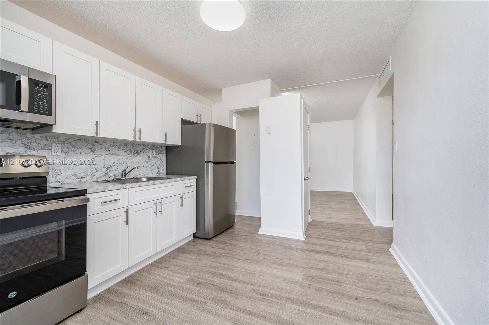 444 SW 27th Avenue, #42, Miami, Miami, FL 33135 Kitchen featuring white Shaker-style cabinetry, stainless steel appliances, stone-patterned backsplash, and wood-finish flooring
