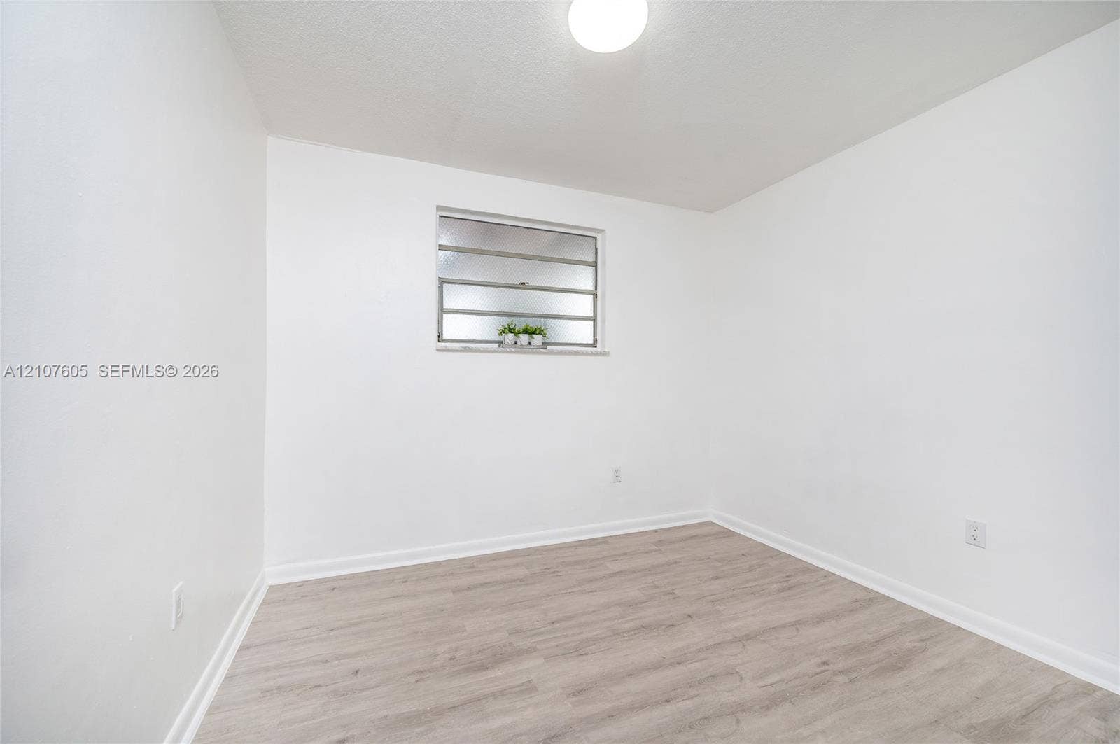 444 SW 27th Avenue, #42, Miami, Miami, FL 33135 Neutral interior space featuring wood-finish flooring, crisp white walls, a flush-mount ceiling light, and jalousie-style window