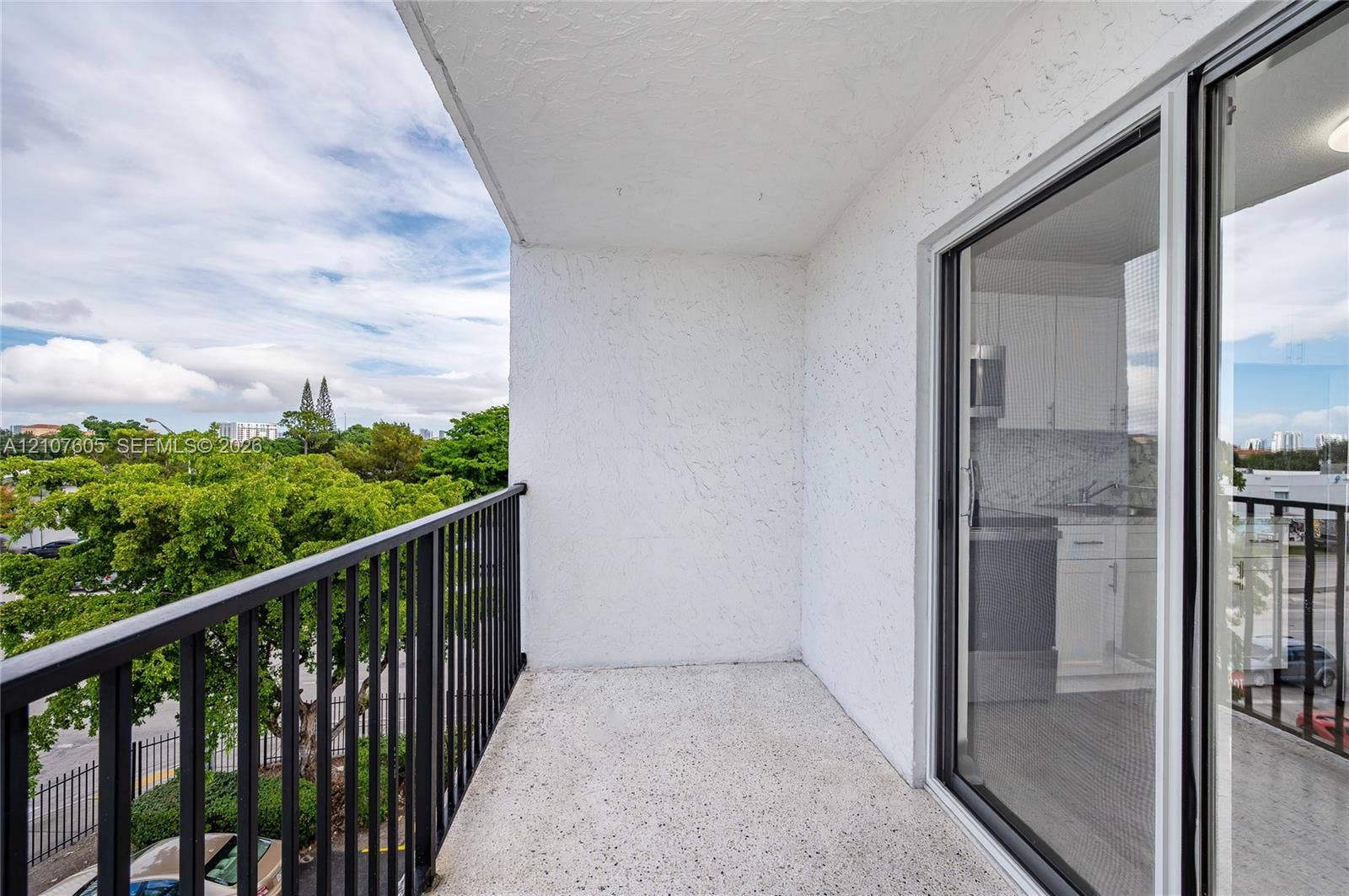 444 SW 27th Avenue, #42, Miami, Miami, FL 33135 Private balcony featuring a concrete floor, black metal railing, and textured stucco walls, accessible via sliding glass doors